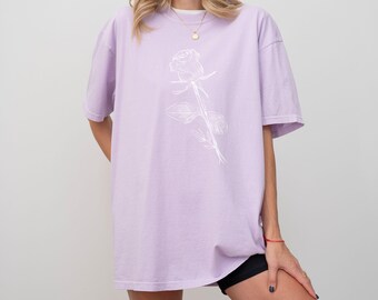 May include: A lavender oversized t-shirt with a white outline of a rose on the front.