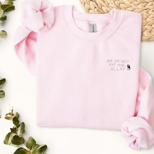 May include: Pink sweatshirt with the text "WE DO NOT EAT OUR ALLIES" and a small black dragon graphic.
