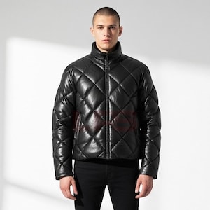 Puede incluir: Chaqueta acolchada negra con cuello alto y cremallera completa. La chaqueta tiene un patrón de diamantes y un acabado brillante. El modelo lleva pantalones negros. Una elegante opción de abrigo.