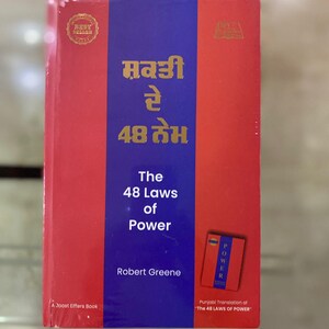 以下が含まれることがあります： ロバート・グリーン著「The 48 Laws of Power」という赤と青の表紙の本。この本はオリジナル作品のパンジャブ語訳です。本の表紙には「ਸ਼ਕਤੀ रे 48 तेभ」という金色の文字が書かれています。