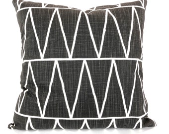 May include: Square decorative pillow with a dark gray textured fabric and a white geometric triangle pattern. The pillow is a square shape and appears to be made of a soft material.