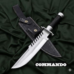 May include: A large, silver survival knife with a serrated blade and black handle, in a black leather sheath. The knife has a guard and a textured handle. The text "SCHWARZENEGGER COMMANDO" is visible.