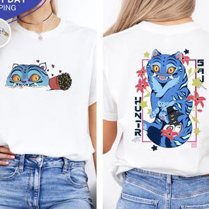 May include: White t-shirt featuring a blue tiger design on the front and back. The front design shows a blue tiger peeking over a line with a flower pot. The back design has a blue tiger with text and flowers.