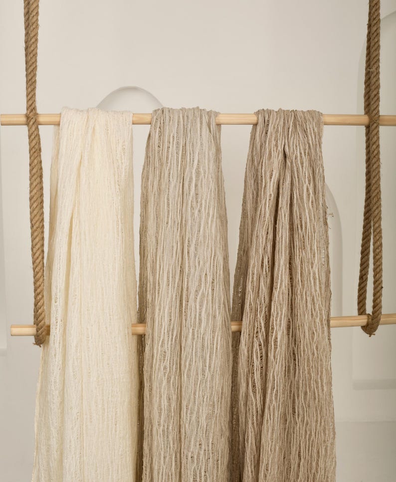 Pu&ograve; includere: Tre pezzi di tessuto appesi a un'asta di legno. Il tessuto &egrave; di colore beige chiaro, beige medio e beige scuro. Il tessuto ha un aspetto testurizzato e intrecciato.