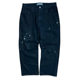 May include: Black denim jeans with white paint splatters. The jeans have a classic five-pocket design, a button and zipper closure, and a straight leg fit. The brand name "SILVER TAB" is visible on the waistband.