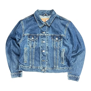 May include: A classic blue denim jacket with a button-up front, two chest pockets, and side pockets. The jacket has a collared neckline and is made of a medium-wash denim material. The Levi Strauss & Co. label is visible on the inside of the collar.