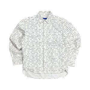 May include: White button-down shirt with long sleeves, covered in black handwritten text. The shirt has a classic collar and a curved hemline. The text appears to be a series of phrases and words.