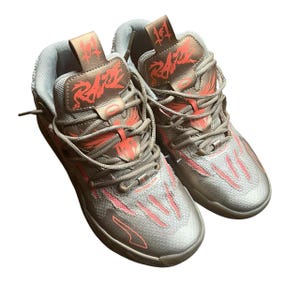 以下が含まれることがあります： シルバーとコーラルのアスレチックシューズのペア。シューズは、コーラルのアクセントと、タンにスタイリッシュなフォントで「Raze」の文字が特徴のメッシュデザインです。靴ひもとトリムは、お揃いのシルバーカラーです。