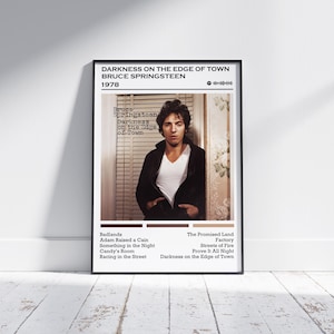 May include: Black framed poster featuring Bruce Springsteen's "Darkness on the Edge of Town" album cover. The poster includes the album title, artist name, and tracklist. The image shows Springsteen in a black jacket and white shirt.