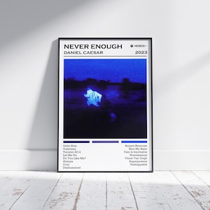 May include: A framed poster with the text "NEVER ENOUGH" and "DANIEL CAESAR" in white. The poster features a dark blue image with a figure. Below are song titles and the year 2023.