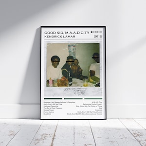 Puede incluir: Póster enmarcado en negro con la portada del álbum "Good Kid, M.A.A.D City" de Kendrick Lamar. La imagen es una foto estilo Polaroid de varias personas sentadas a una mesa. El título del álbum y el nombre del artista están impresos en la parte superior.