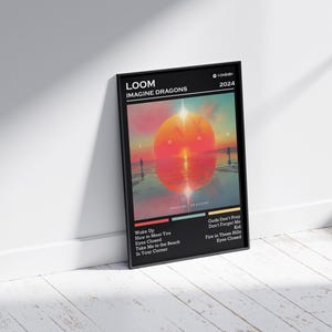 Puede incluir: P&oacute;ster enmarcado en negro del &aacute;lbum "LOOM" de Imagine Dragons. La obra de arte muestra una puesta de sol sobre el agua con siluetas. Los t&iacute;tulos de las canciones, como "Wake Up" y "Eyes Closed", est&aacute;n listados debajo. Tambi&eacute;n se ve el a&ntilde;o 2024.