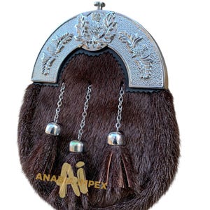 Puede incluir: Un sporran de piel marrón con un diseño de cardo y hojas de plata en la solapa superior. El sporran tiene tres cadenas de plata con borlas.