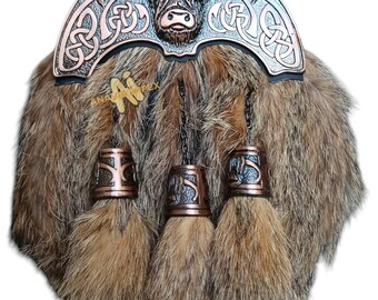 Op de afbeelding: Een sporran van bruin bont met een metalen kiltpin met een Hooglandkoe-ontwerp en Keltische knoopwerk. De sporran heeft drie kwastjes met metalen accenten.