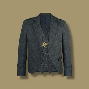 Puede incluir: Un traje de tweed gris oscuro, que incluye una chaqueta y un chaleco, se muestra sobre un fondo neutro. La chaqueta presenta solapas con muescas, puños abotonados y charreteras. El chaleco tiene una parte delantera abotonada. El traje está diseñado para un look clásico.