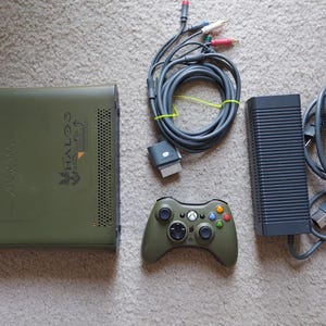 Könnte beinhalten: Eine grüne Xbox 360 Konsole mit einem Halo 3 Special Edition Design, ein schwarzer Xbox 360 Controller, ein schwarzes Netzteil und ein schwarzes Kabel mit mehreren Steckern.