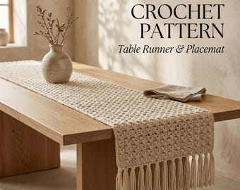 May include: A cream-coloured crochet table runner with a textured stitch pattern and long fringe tassels at the end. The text EASY BOHO CROCHET PATTERN Table Runner & Placemat is displayed in black lettering above the runner on a wooden table.