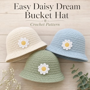 May include: Three crochet bucket hats in cream, light blue, and sage green, each adorned with a daisy applique. The hats are displayed on a light wood surface. Text at the top reads "Easy Daisy Dream Bucket Hat Crochet Pattern."