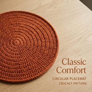 Op de afbeelding: Een cirkelvormige, roestkleurige gehaakte placemat met een dicht, spiraalvormig steekpatroon. De tekst "Classic Comfort" is in bruin gedrukt, gevolgd door de woorden "CIRCULAR PLACEMAT CROCHET PATTERN" in kleinere hoofdletters.