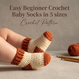 May include: Crochet baby socks featuring a two-tone design with cream-coloured feet and rust-orange cuffs, heels, and toes. The text reads: Easy Beginner Crochet Baby Socks in 5 sizes Crochet Pattern. A ball of yarn and hooks are visible.
