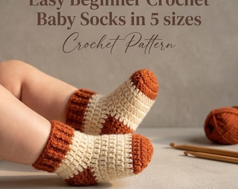 May include: Crochet baby socks featuring a two-tone design with cream-coloured feet and rust-orange cuffs, heels, and toes. The text reads: Easy Beginner Crochet Baby Socks in 5 sizes Crochet Pattern. A ball of yarn and hooks are visible.