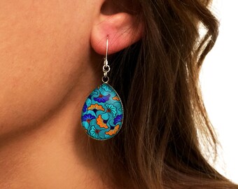 May include: Teal blue teardrop shaped earrings with a floral pattern in orange, blue, and white.