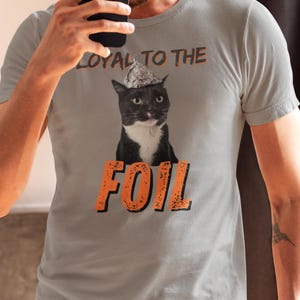 Maglietta unisex con gatto e cappello di carta stagnola: divertente teoria del complotto immagine 3