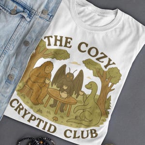 Cozy Cryptid Club T Shirt | Cute Bigfoot Mothman Nessie Tea Party Tee | Cryptidcore Forest Friends Shirt | Unisex Whimsical Mythic Top