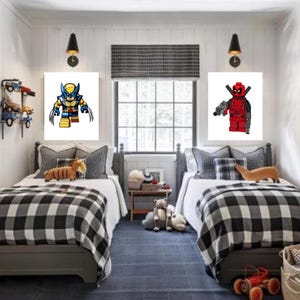 May include: Two twin beds with black and white checked bedding in a room with white walls. There are two framed pictures on the walls, one with a cartoon image of Wolverine and the other with a cartoon image of Deadpool.