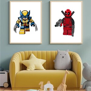 May include: Two framed prints of Lego superhero characters. The print on the left features Wolverine in his signature yellow and blue costume. The print on the right features Deadpool in his red and black costume.