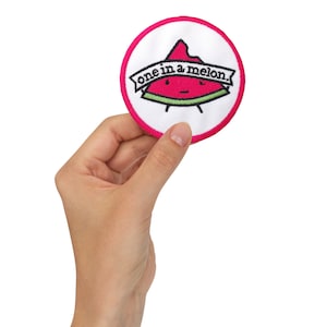 May include: A white and pink round embroidered patch with a watermelon slice design. The watermelon has a face and the text "one in a melon." is above it.