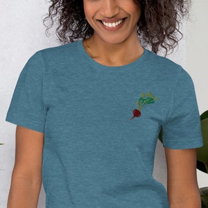 May include: A blue heather t-shirt with a small embroidered image of a red beet with green leaves.