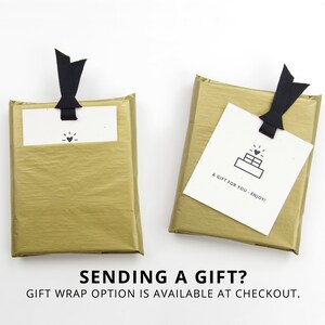 May include: Two gold gift boxes with black ribbon bows and white gift tags. The tag on the left box has a heart icon. The tag on the right box has a cake icon and the text "A gift for you - Enjoy!"