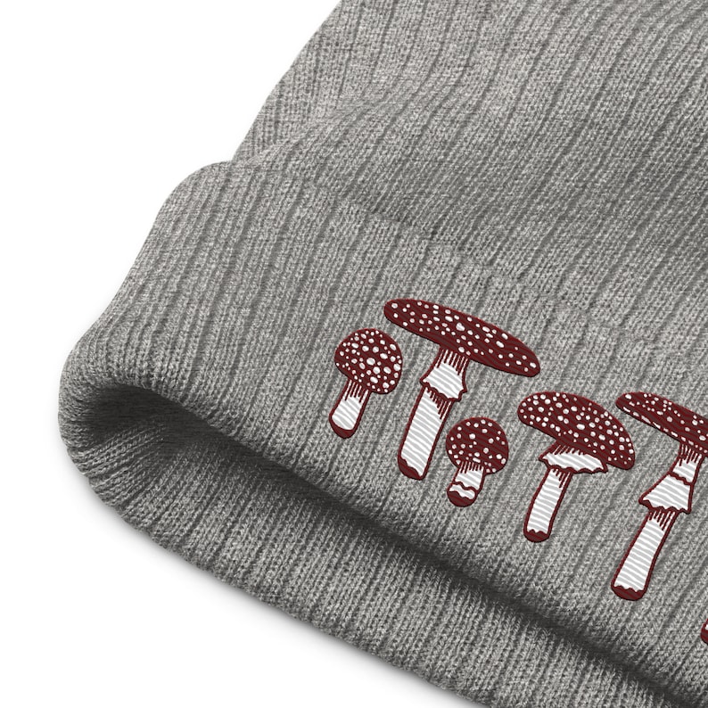 May include: Gray knit beanie with a row of embroidered red and white mushrooms.
