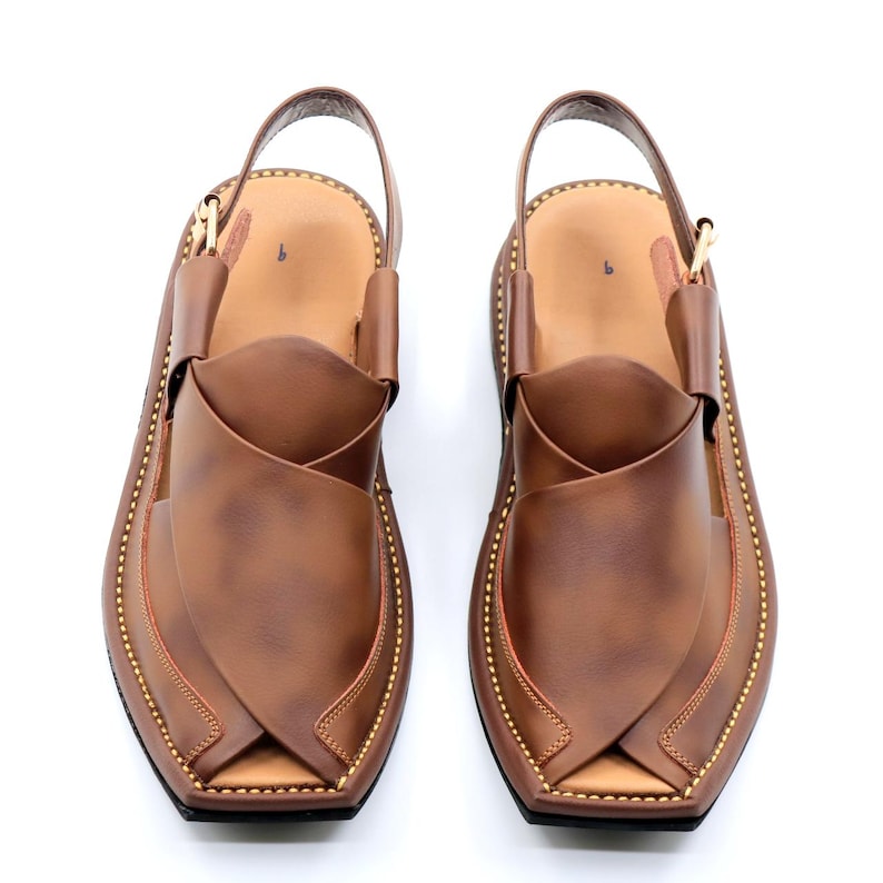 May include: A pair of brown leather sandals with a strap across the top and a pointed toe. The sandals have a gold stitching detail around the edges.