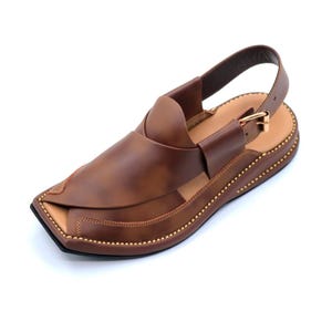 May include: Brown leather sandals with a strap and buckle. The sandals have a pointed toe and a decorative stitch around the edge.