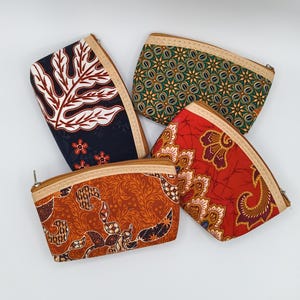 Op de afbeelding: Vier kleine etuis met ritssluiting en kleurrijke batikpatronen. De etuis hebben ontwerpen in tinten rood, oranje, groen en marineblauw. Elk etui heeft een beige rand en een ritssluiting, perfect voor kleine spullen.