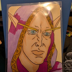 May include: A hand-drawn illustration of a pointed-eared character wearing a purple hooded garment with gold trim. The figure has light skin, blue eyes, and thin yellow eyebrows, set against a light background inside a clear protective sleeve.