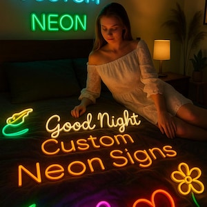 Puede incluir: Una mujer está rodeada de letreros de neón de colores. Los letreros incluyen las palabras "CUSTOM NEON" en azul y verde, y "Good Night Custom Neon Signs" en naranja. Otras formas de neón incluyen una luna creciente, corazones y una flor.