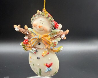 Decorative Resin Snowman Christmas ornament featuring a smiling snowman with angel wings, twig-like arms, and a red cardinal accent,