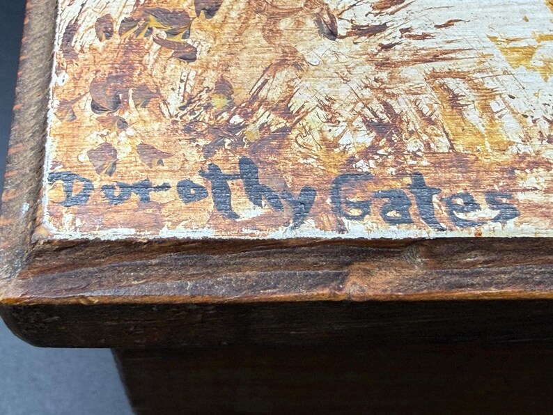 May include: Close-up of a wooden box with a painted top. The artwork features a blend of brown, tan, and white hues. The artist's signature, "Dorothy Gates," is visible in black script. The box has a dark brown wooden frame.