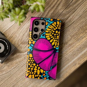 Könnte beinhalten: Eine Handyhülle mit einem farbenfrohen abstrakten Design in Pink, Gelb, Blau und Schwarz. Die Hülle hat einen Kameraausschnitt und einen erhöhten Rand an den Kanten.