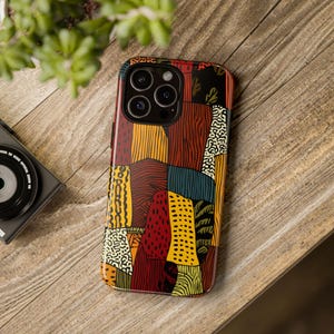 May include: A patterned phone case with a patchwork design. The case features a variety of colours, including red, yellow, orange, and black. The case is made of a glossy material and has a camera cutout.
