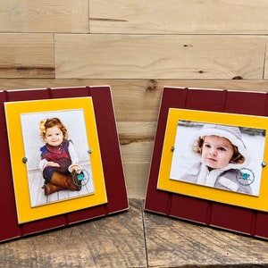 May include: Two wooden picture frames with a red outer frame and a yellow inner frame. Each frame holds a photo of a young child.