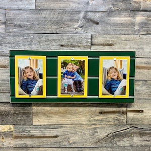 May include: A green wooden picture frame with three yellow picture frames inside. The frames are holding photos of children.