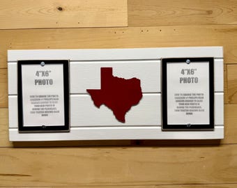 May include: A white horizontal wooden board featuring two black 4 inch by 6 inch photo frames and a dark red cutout of the state of Texas centered between them. The frames include printed instructions for changing photos using Phillips head screws.