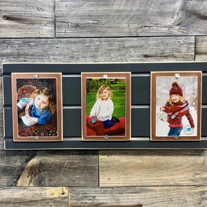 May include: Three framed photographs of children, each with a different background. The frames are made of wood with a dark gray finish and a light brown inner border. The photos are mounted on a dark gray wooden background.