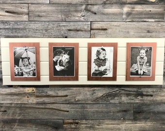 May include: Four black and white photos of children are displayed in copper-colored frames on a white wooden wall. The frames are attached to the wall with small silver screws.