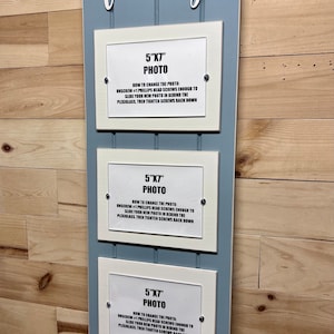 May include: A light blue wooden frame with the word "family" in white lettering. The frame has three white picture frames with instructions on how to change the photos. Each frame is labelled "5"x"7" Photo".