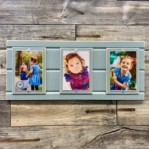 May include: A gray wooden picture frame with three separate picture frames inside. The frames are holding pictures of children. The pictures are in color and the children are smiling.